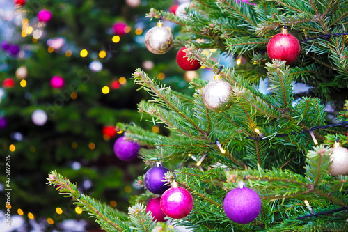 Christmas holidays background. Close-up view of fir tree branches with bright balls, xmas ornaments and toys and bright warm lights or garland. Festive and New Year background