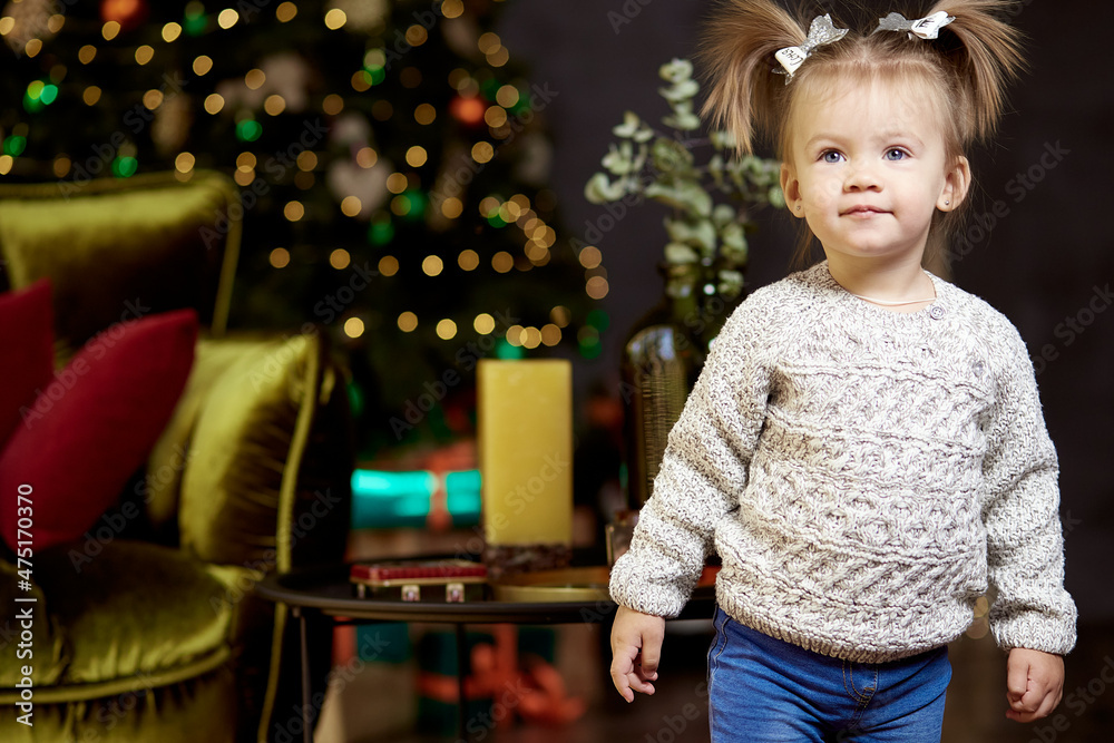 Festive cute little girl near Christmas tree in festive interior . Selective focus Festive cute little girl near Christmas tree in festive interior . Selective focus
