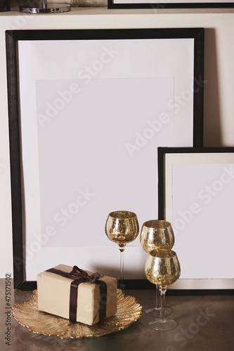 Wall picture frames mock up for design or text. Wine glasses and giftbox. Modern interior