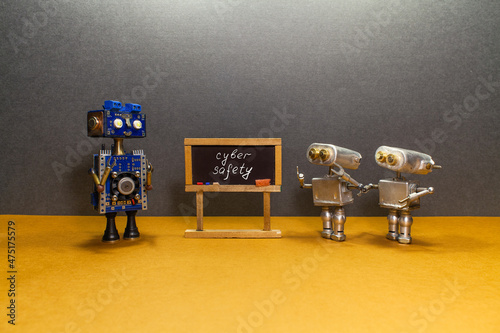 The robot teacher tells the little students a lesson about cyber safety. Toy bots at black chalkboard, handwritten text. Artificial intelligence and machine learning technology concept