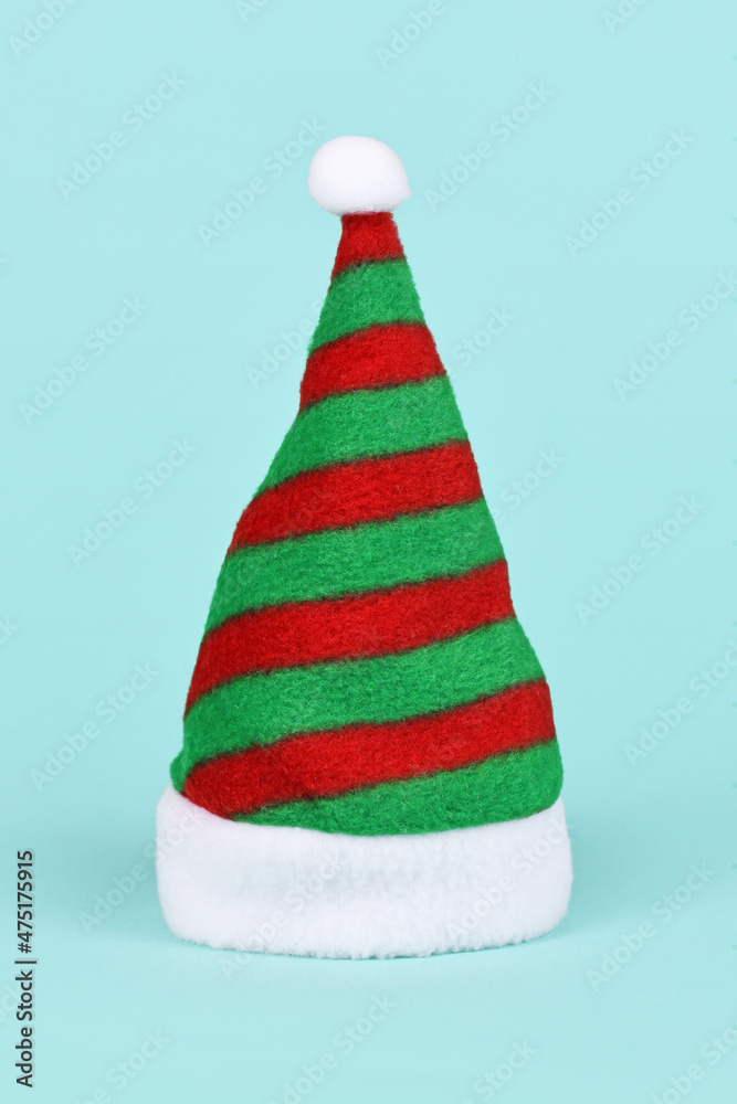 Striped green and red Santa hat on blue background Striped green and red Santa hat on blue background