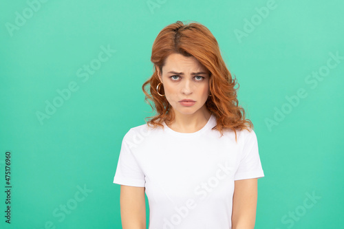 sad female fashion model. pretty look of young girl. portrait of redhead lady on blue background