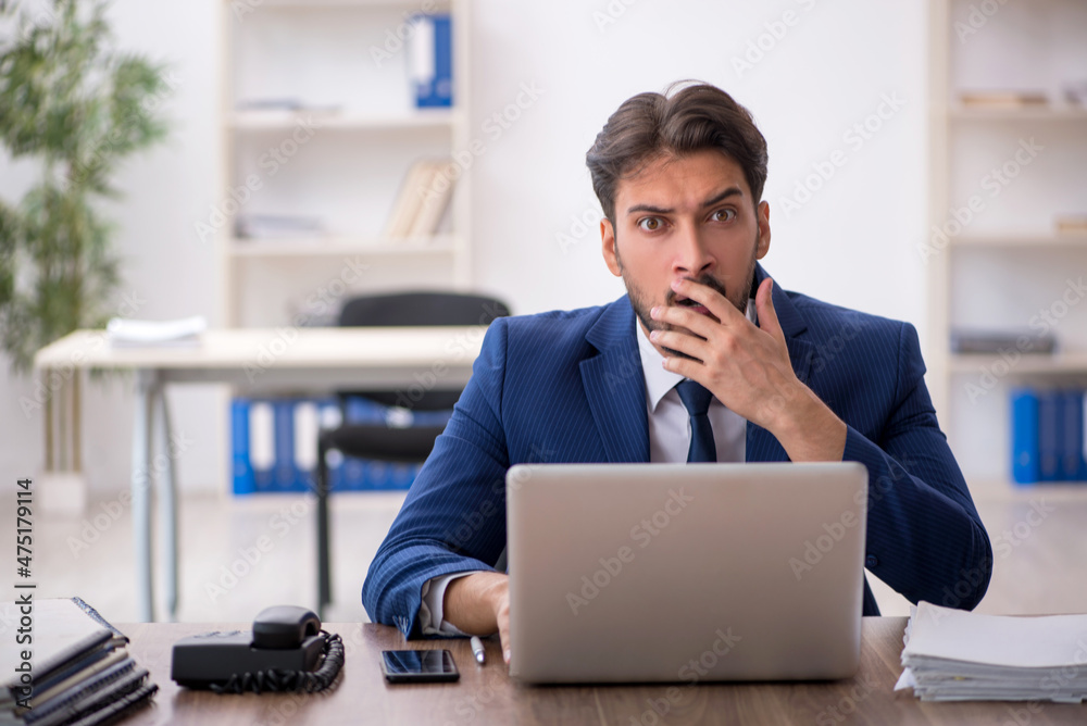 Young male employee unhappy with excessive work in the office Young male employee unhappy with excessive work in the office