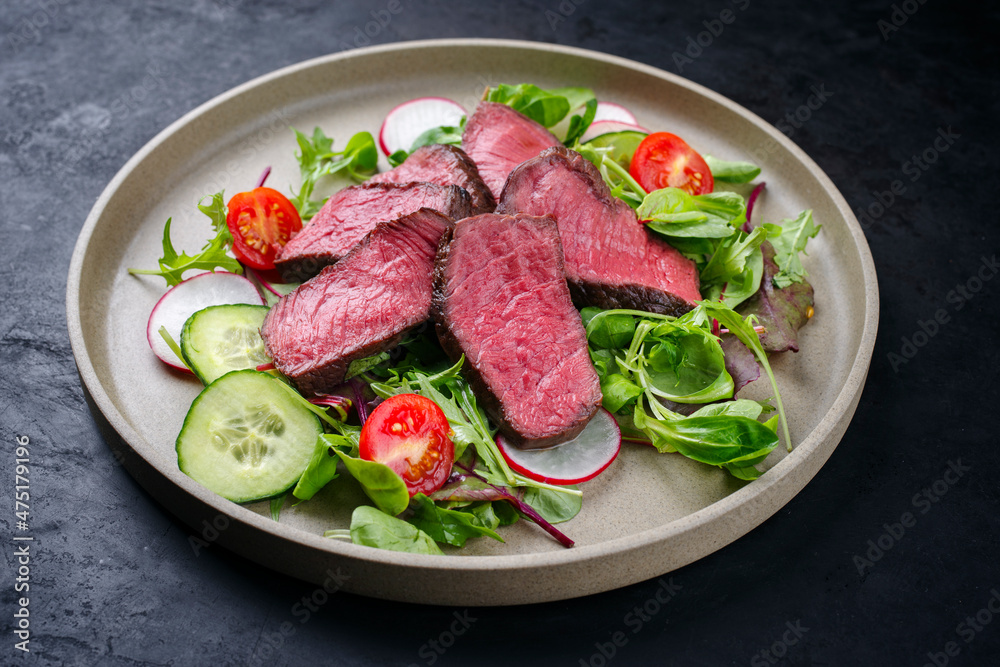 Modern style traditional fried dry aged bison beef rump steak slices with vegetable and lettuce served as close-up on a Nordic design plate with copy space Modern style traditional fried dry aged bison beef rump steak slices with vegetable and lettuce served as close-up on a Nordic design plate with copy space