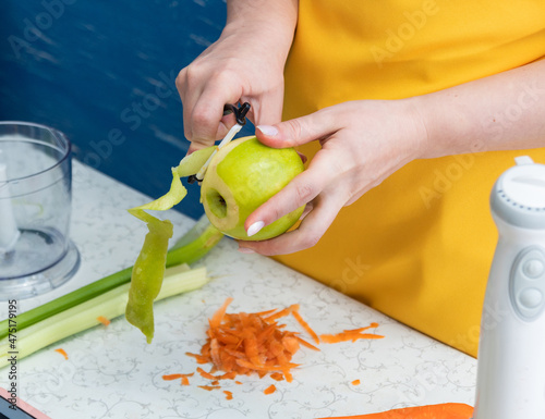 Peeling an apple with knife. There are other ingredients and tools for making a smoothie on the table. Selective focus. Healthy eating.