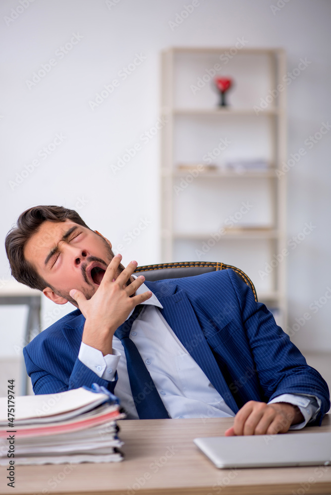 Young male employee extremely tired in the office Young male employee extremely tired in the office