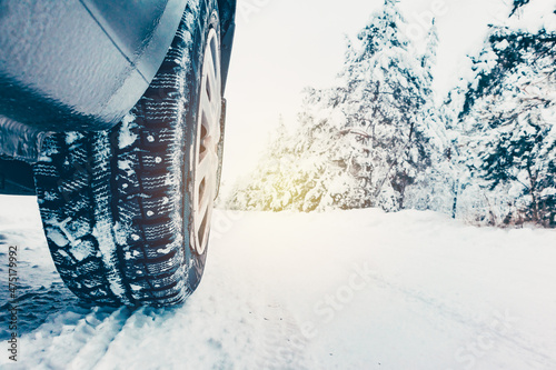 Fotografi studded car tire on a winter snow-covered road in the forest, winter journey
