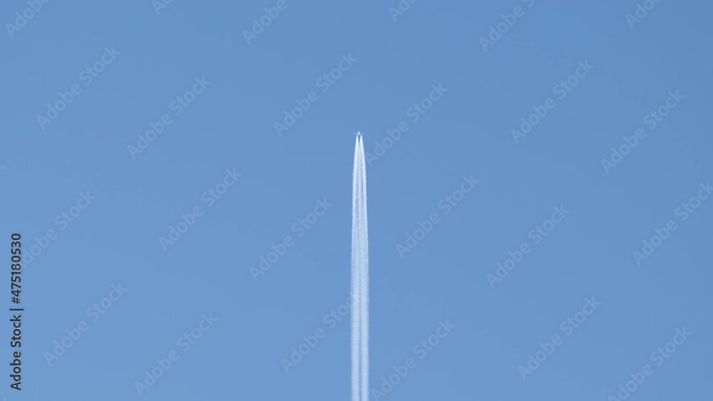 Distant passenger jet plane flying on high altitude on clear blue sky leaving white smoke trace of contrail behind. Air transportation concept Distant passenger jet plane flying on high altitude on clear blue sky leaving white smoke trace of contrail behind. Air transportation concept