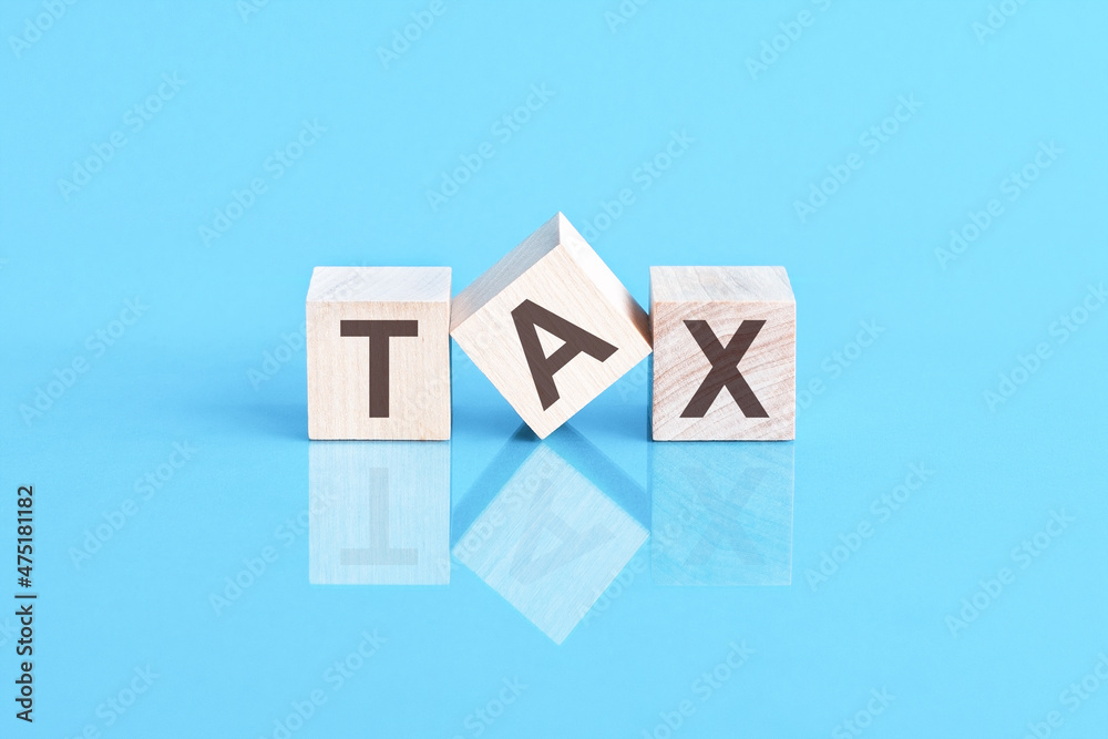 word tax from wooden blocks with letters, front view on blue background. Tax concept with wooden block. word tax from wooden blocks with letters, front view on blue background. Tax concept with wooden block.