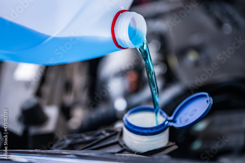 Pouring antifreeze. Filling a windshield washer tank with an antifreeze in winter cold weather... photo