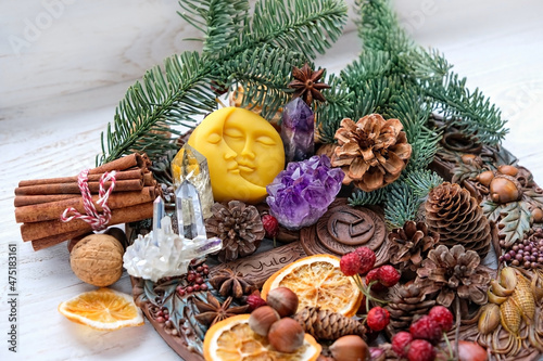 Wiccan altar for Yule sabbat. Sun-moon amulet, wheel of the year, gemstones, nuts, cones, dry orange slices. Esoteric Ritual for Christmas, Yule, Winter Solstice