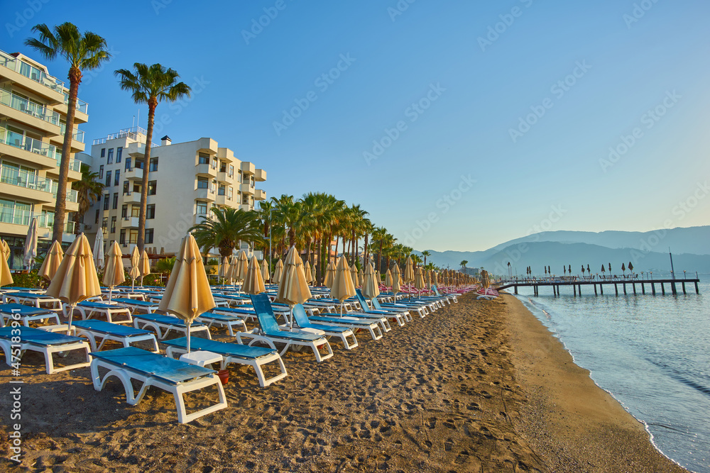 beach on the sea in cloudless weather. Sunset on a sandy beach with umbrellas and sun loungers