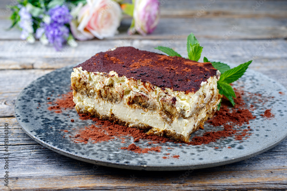 Modern style traditional Italian tiramisu served as close-up on a Nordic design plate on a wooden board Modern style traditional Italian tiramisu served as close-up on a Nordic design plate on a wooden board