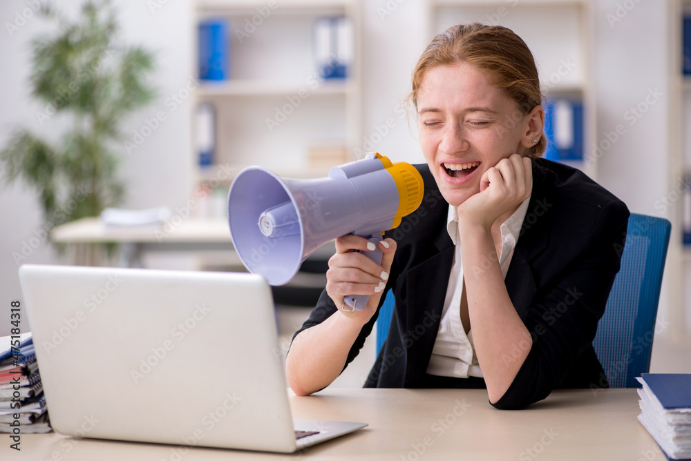 Young female employee holding megaphone in the office Young female employee holding megaphone in the office
