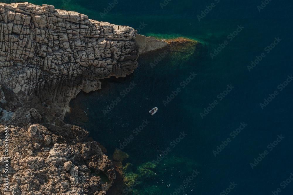 cliff-top view of a small bay with a boat on a sunny day