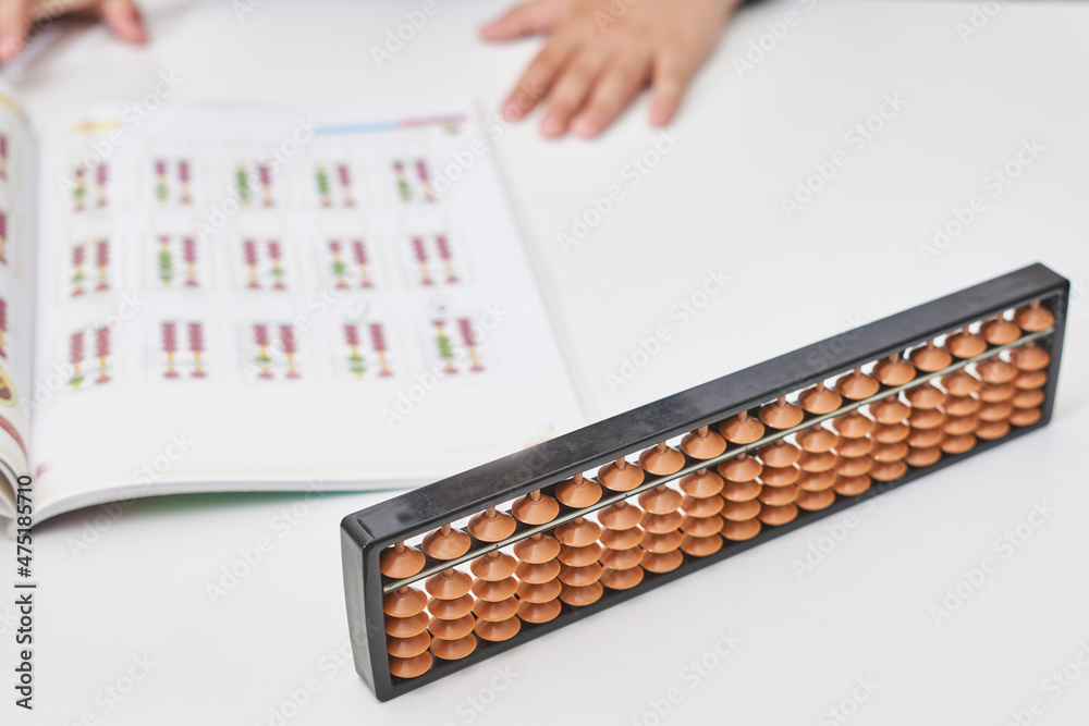 Doing mental math or mental arithmetic. Hand of little boy using abacus for calculating. Learning to use abacus on mental math courses. A kid doing math at home with abacus Doing mental math or mental arithmetic. Hand of little boy using abacus for calculating. Learning to use abacus on mental math courses. A kid doing math at home with abacus