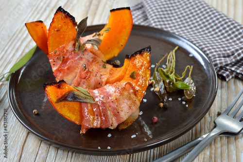 Hokkaido-Kürbisschnitten im Salbei-Speckmantel aus dem Ofen – Pumpkin gaps wrapped in bacon with sage leaves and thyme, baked in olive oil with pepper and salt photo