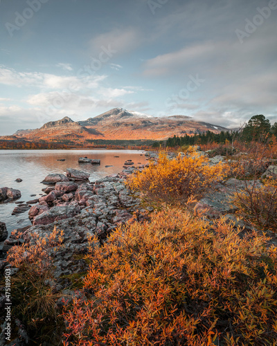Mountain landscape with lake and rocks in Stora Sjöfallet National Park in autumn in Lapland in Sweden from above during sunset.