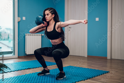 Fototapeta Naklejka Na Ścianę i Meble -  Young woman fitness instructor training in the gym and using kettlebell