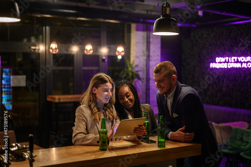 Cheerful colleagues drinking beer in the bar together after work