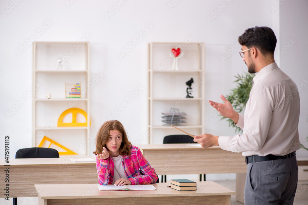 Young male teacher and redhead girl in the classroom