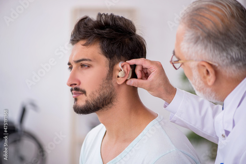 Cuadro en lienzo Young male patient with hearing problem visiting old doctor otor