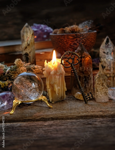 Fotografie Candle, crystal ball, key, gemstones, magic things on dark wooden background