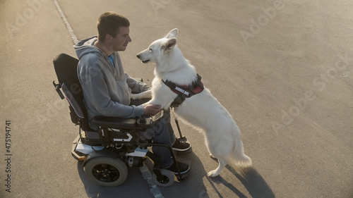 Man with disability with his service dog using electric wheelchair.