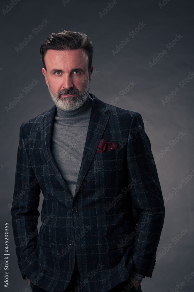 Portrait of a stylish elegant senior businessman with a beard and casual business clothes in photo studio isolated on dark background gesturing with hands Portrait of a stylish elegant senior businessman with a beard and casual business clothes in photo studio isolated on dark background gesturing with hands