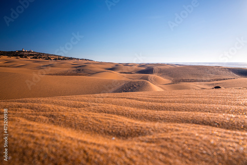 Scenic view of shiny sand dunes and seascape against dramatic cloudy sky