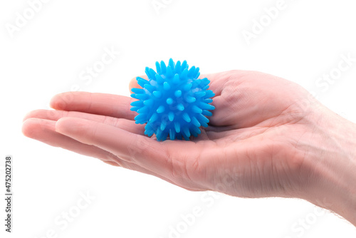 Detail studio shot of blue rubber massage ball lying on palm of a right hand isolated on white background. Contemporary rehabilitation equipment. Physiotherapy tools.
