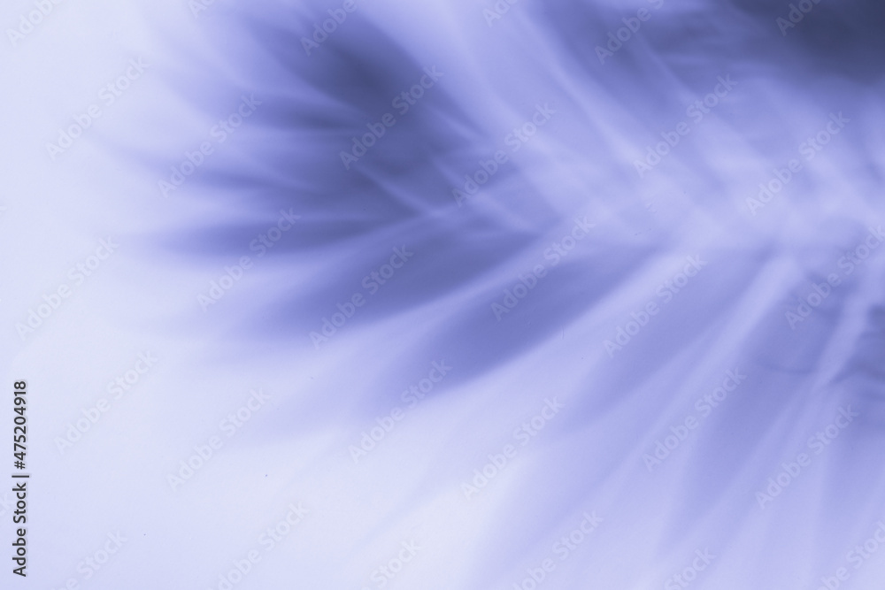 The shadow from the branches of a palm tree on a very peri background. Trendy summer background The shadow from the branches of a palm tree on a very peri background. Trendy summer background