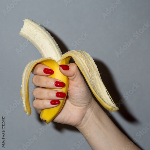 hand with red nails holds a banana
