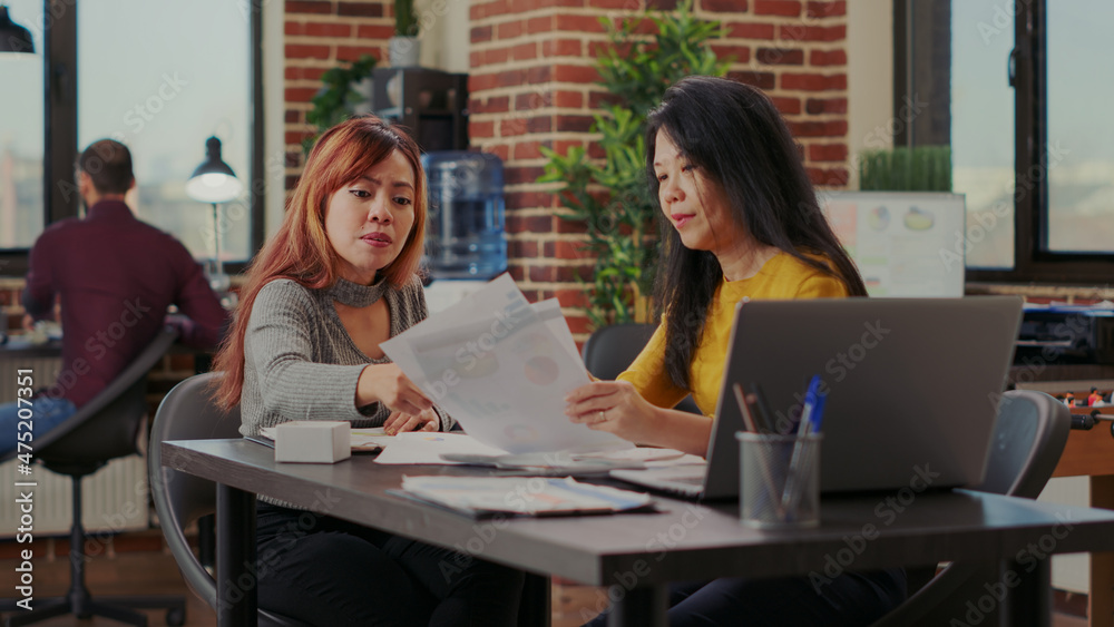 Obraz premium Team of asian women brainstorming strategy ideas in office, starting partnership to help with company growth. Colleagues working with financial statistics and paperwork for development.