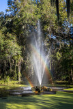 Photo of a fountain in a park with a double rainbow showing in the water spray