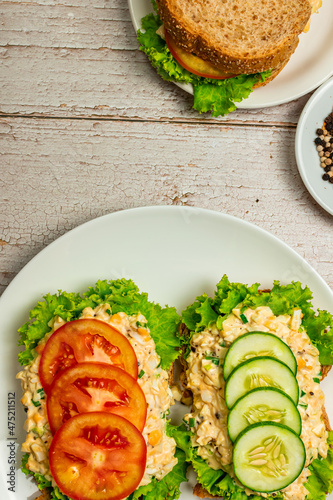 Homemade egg salad sandwich with wholewheat bun,cucumber, tomatoes,lettuce,egg,and cream cheese.  Rustic style. Selective Focus. Top view. Copy space. No.04