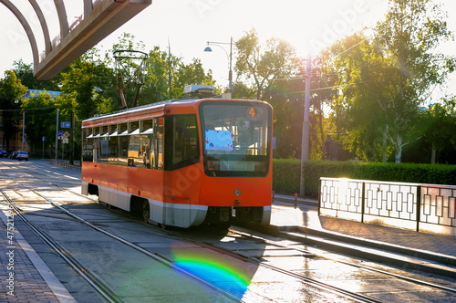 orange tram on the city street on a sunny day near the platform 
