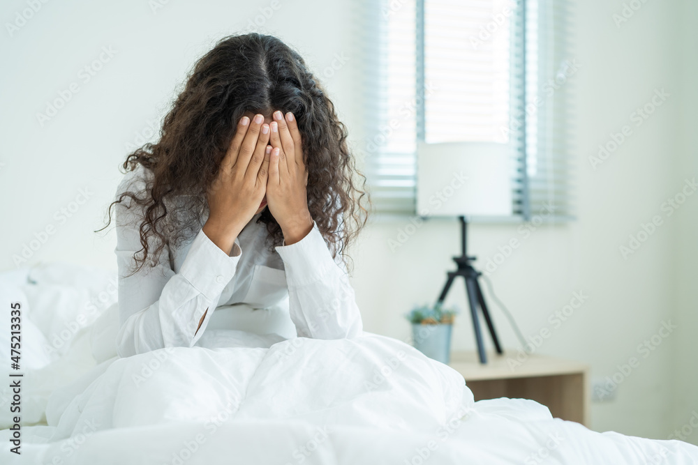 Latino beautiful girl in pajamas feel sick while sit on bed in bedroom Latino beautiful girl in pajamas feel sick while sit on bed in bedroom