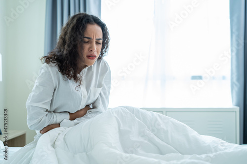 Latino beautiful sick girl in pajamas getting up from sleep in bedroom