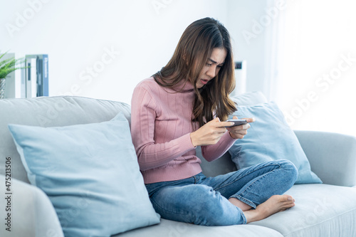 Asian frustrated beautiful woman play mobile game on cellphone at home