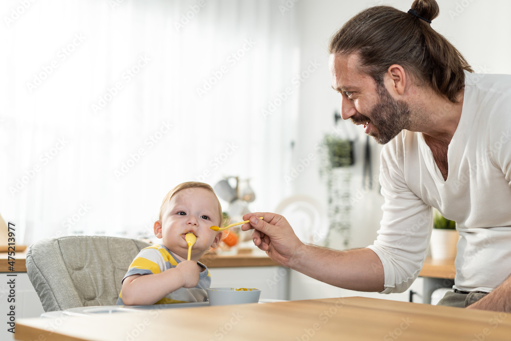 Caucasian beautiful father take care of baby boy toddler in kitchen. Caucasian beautiful father take care of baby boy toddler in kitchen.