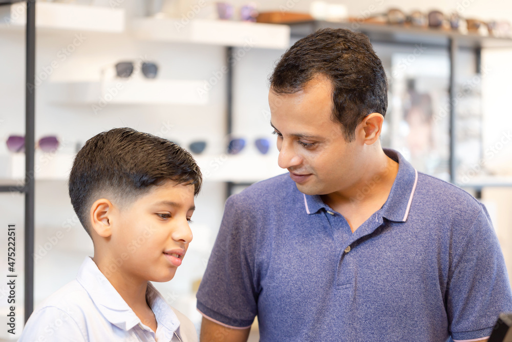 Indian boy and father choosing eyeglasses in optics store Indian boy and father choosing eyeglasses in optics store