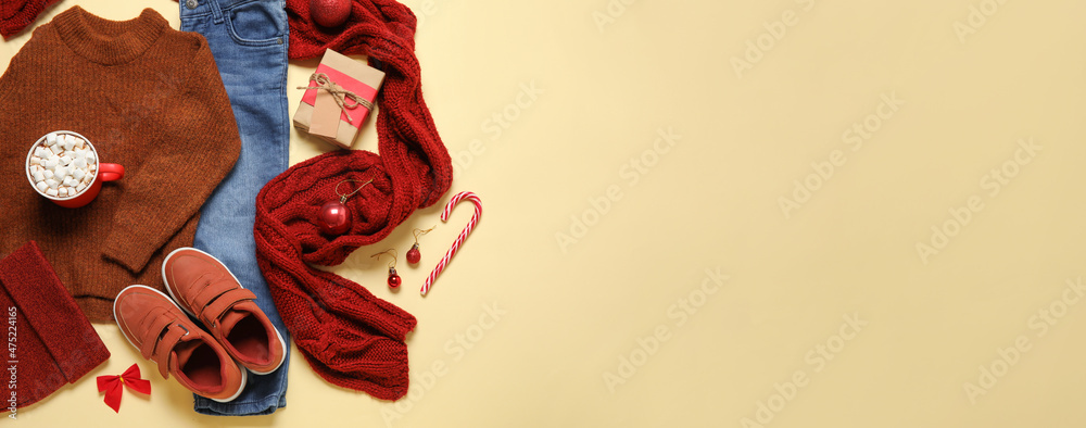 Set of children's clothes with Christmas gift and cup of hot chocolate on color background with space for text