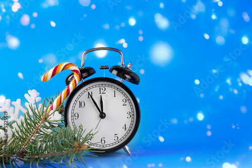 Alarm clock and Christmas symbols on a blue abstract background.