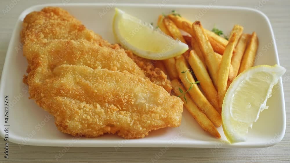 fish and chips - fried fish fillet with potatoes chips and lemon on white plate fish and chips - fried fish fillet with potatoes chips and lemon on white plate