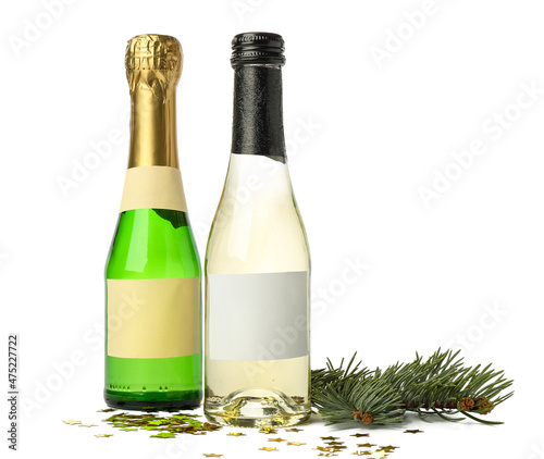 Bottles of champagne with confetti and fir branch on white background