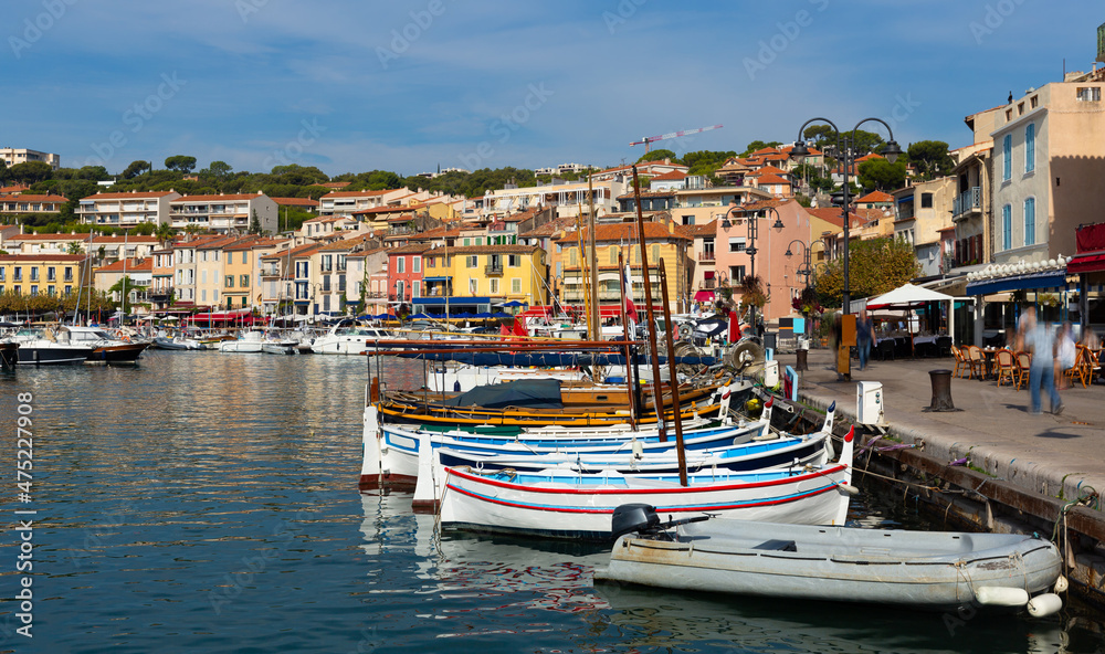 Photo of harbour in French town Cassis with view of fishing boatsand and residential buildings along shore.