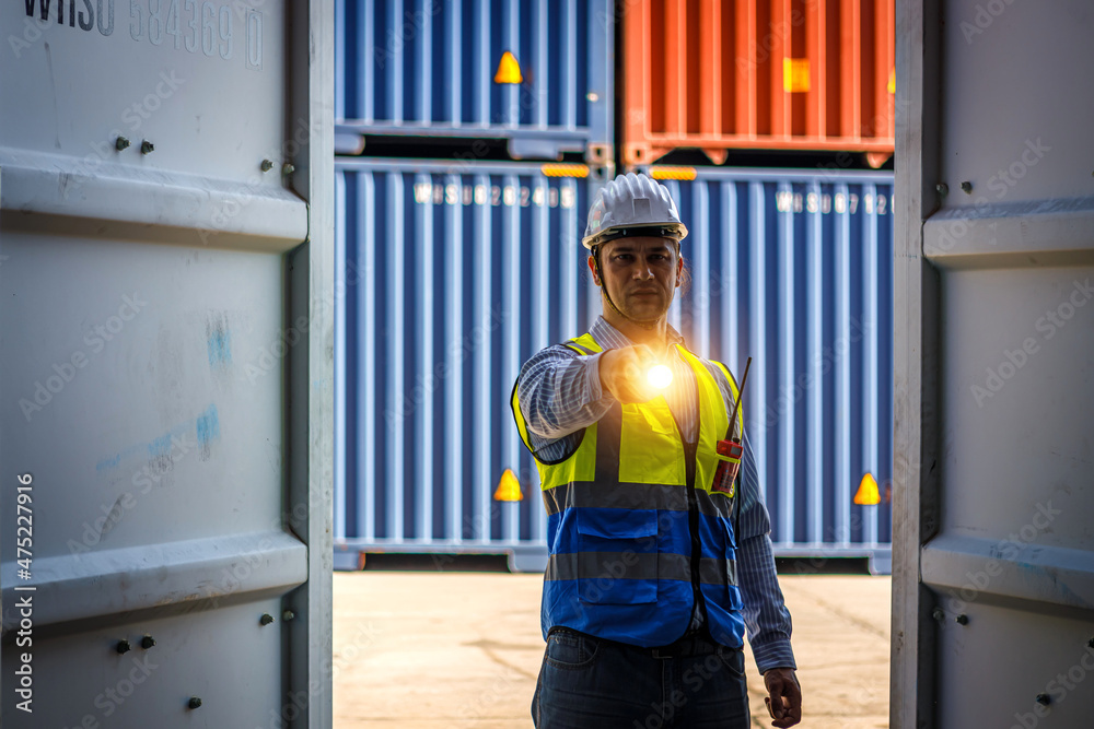 Caucasian male engineer holding a flashlight opens a cargo container. Caucasian male engineer holding a flashlight opens a cargo container.