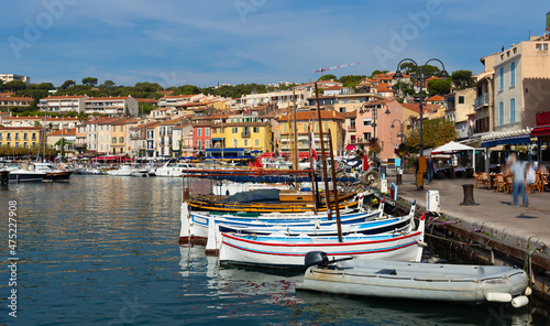 Photo of harbour in French town Cassis with view of fishing boatsand and residential buildings along shore. © JackF
