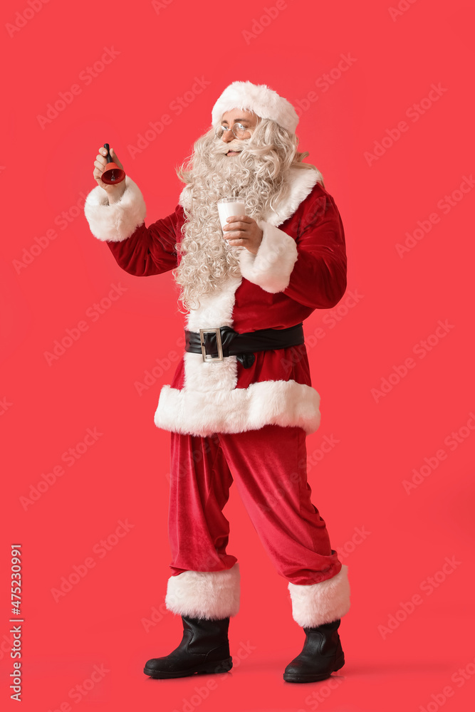 Santa Claus with glass of milk and Christmas bell on red background Santa Claus with glass of milk and Christmas bell on red background